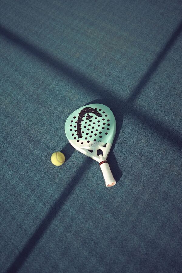 Padelschläger und Ball auf einem Court im Abendlicht
